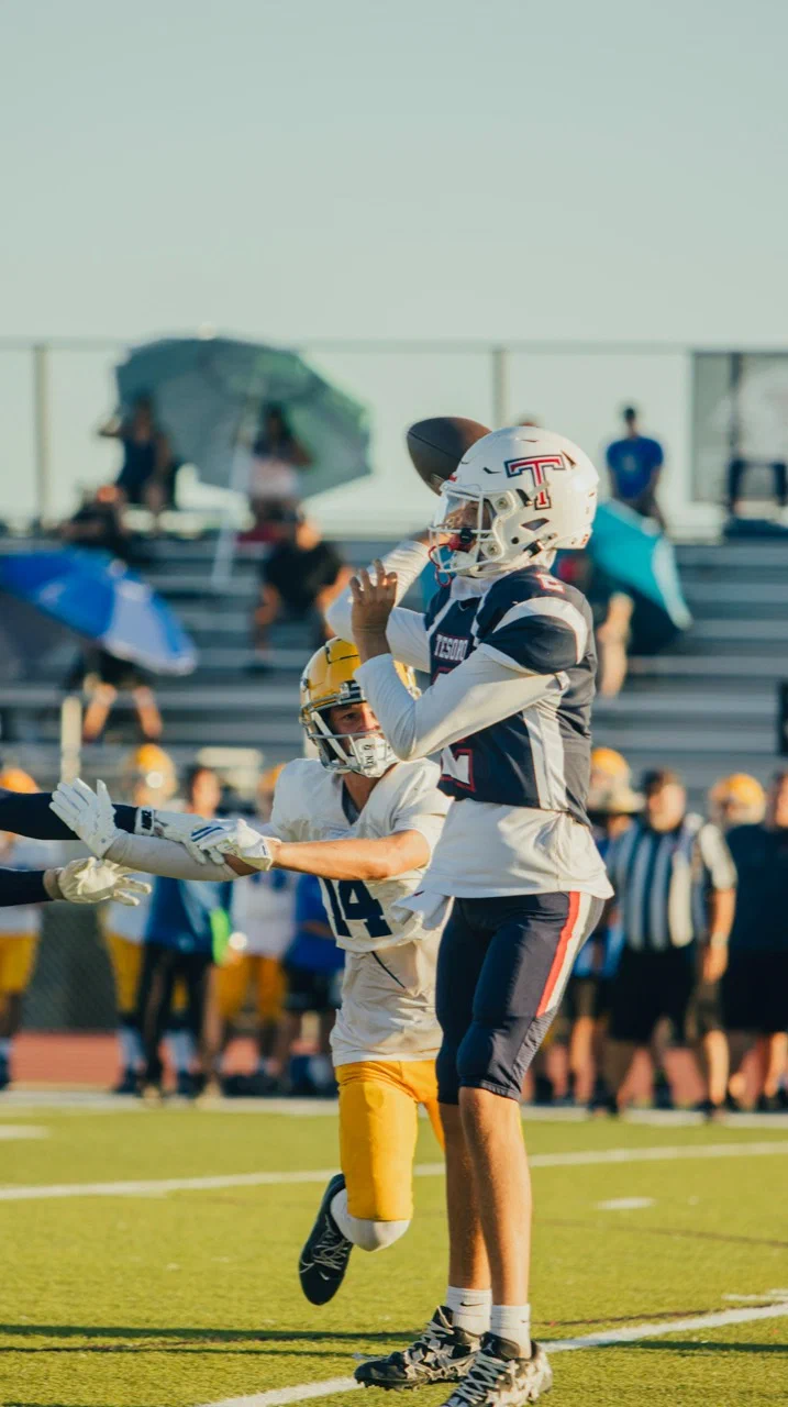 Jayden Hansen throwing the football with a defender close by — 2025 freshman season
